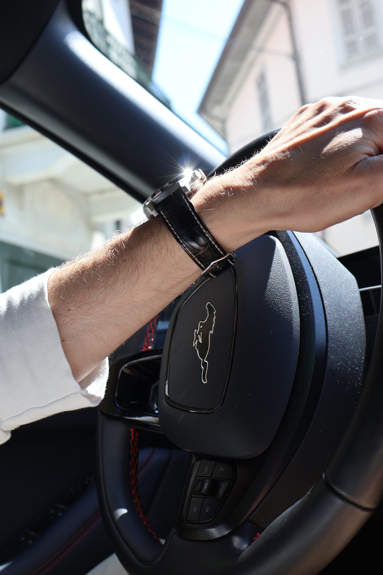 Hand mit Uhr am Lenkrad eines Autos